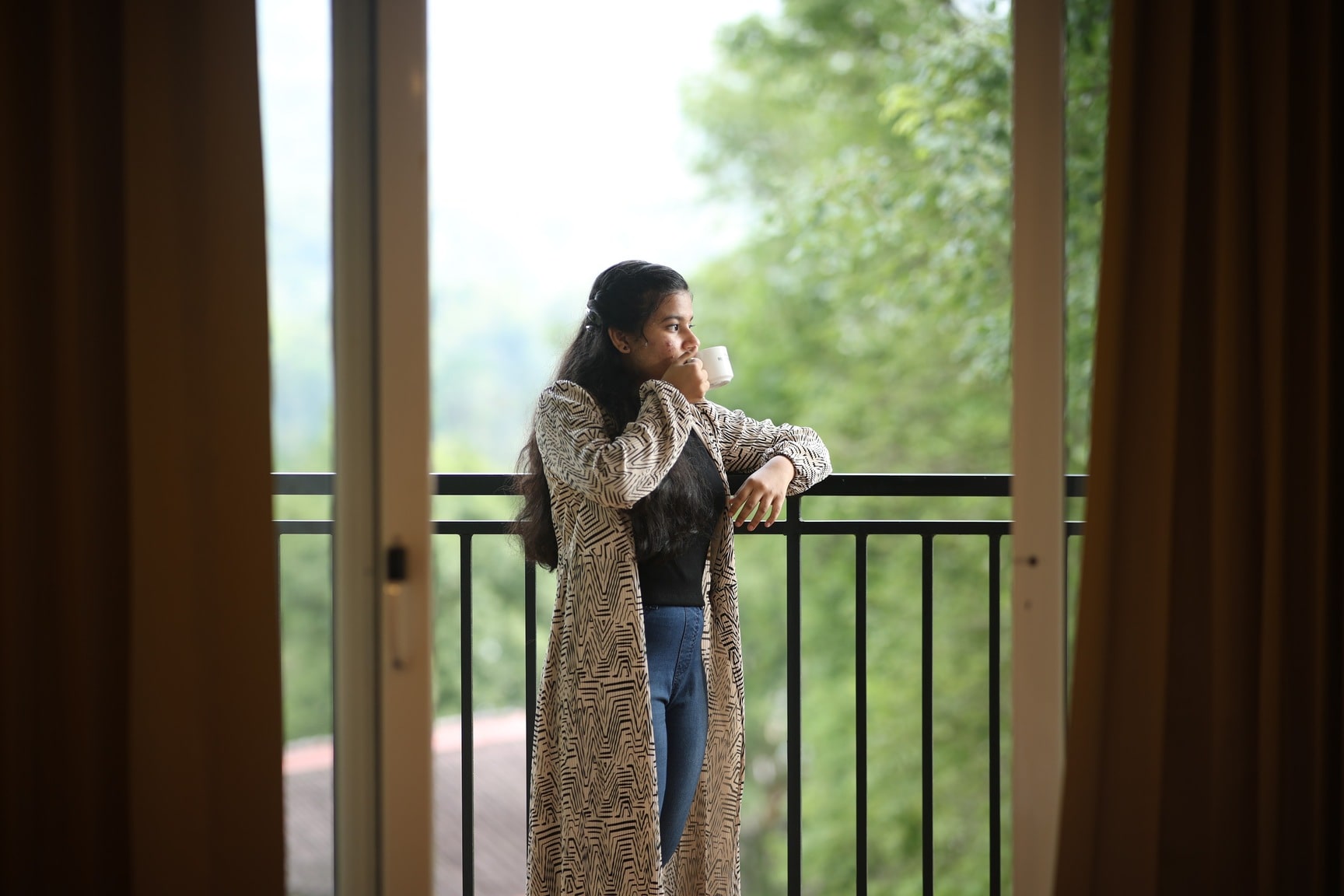 Woman Enjoying Coffee on Balcony with Nature View